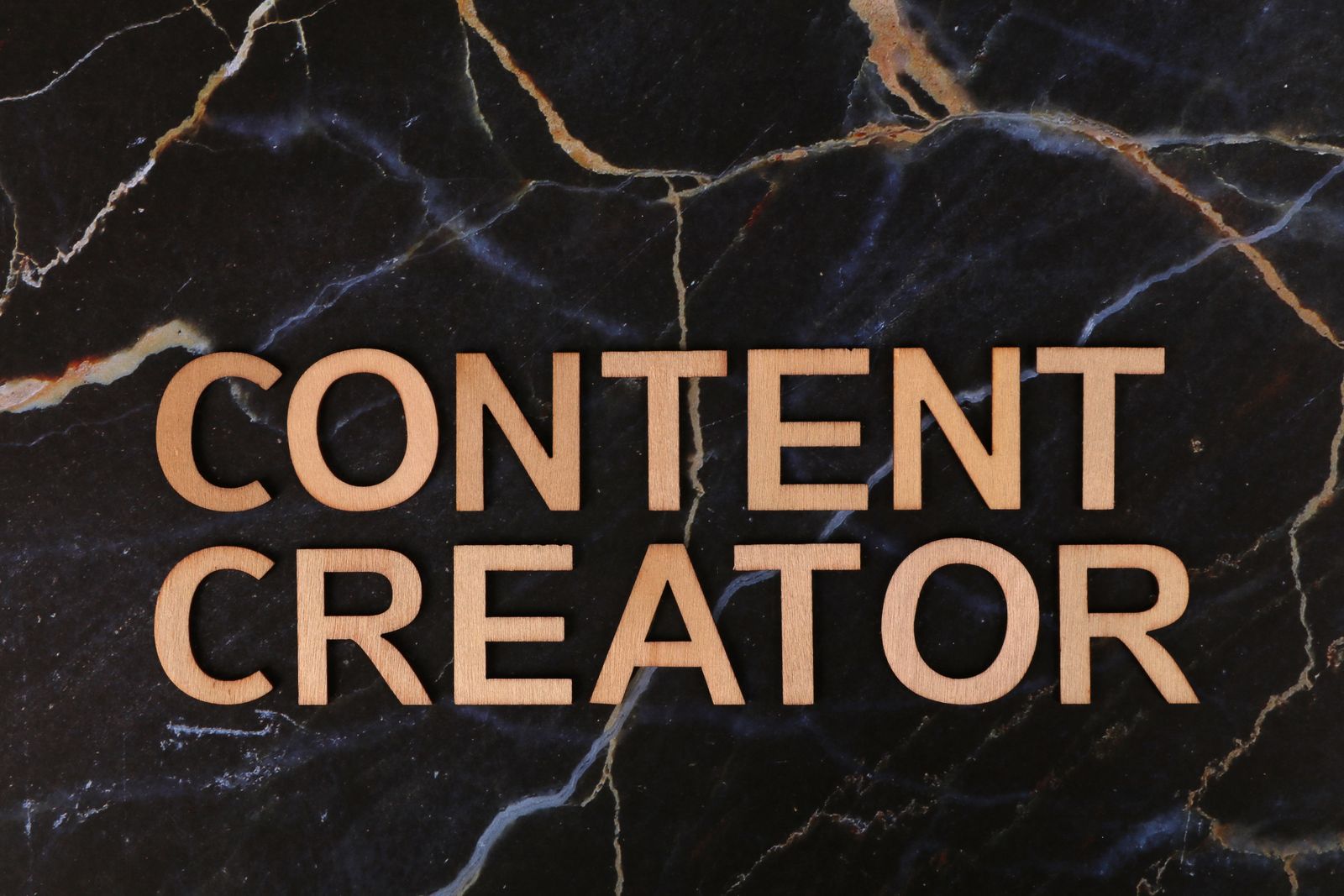 Illustrative photo of wooden content creator text on a marble background
