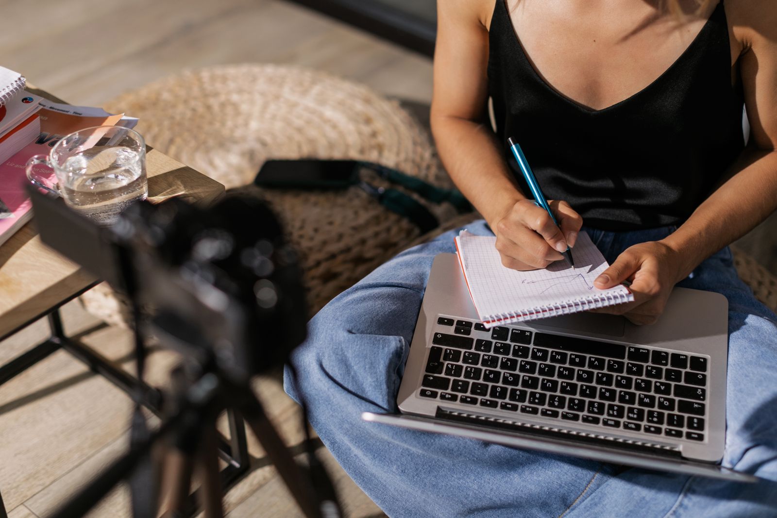 Illustrative photo of a person writing in a notebook with a laptop
